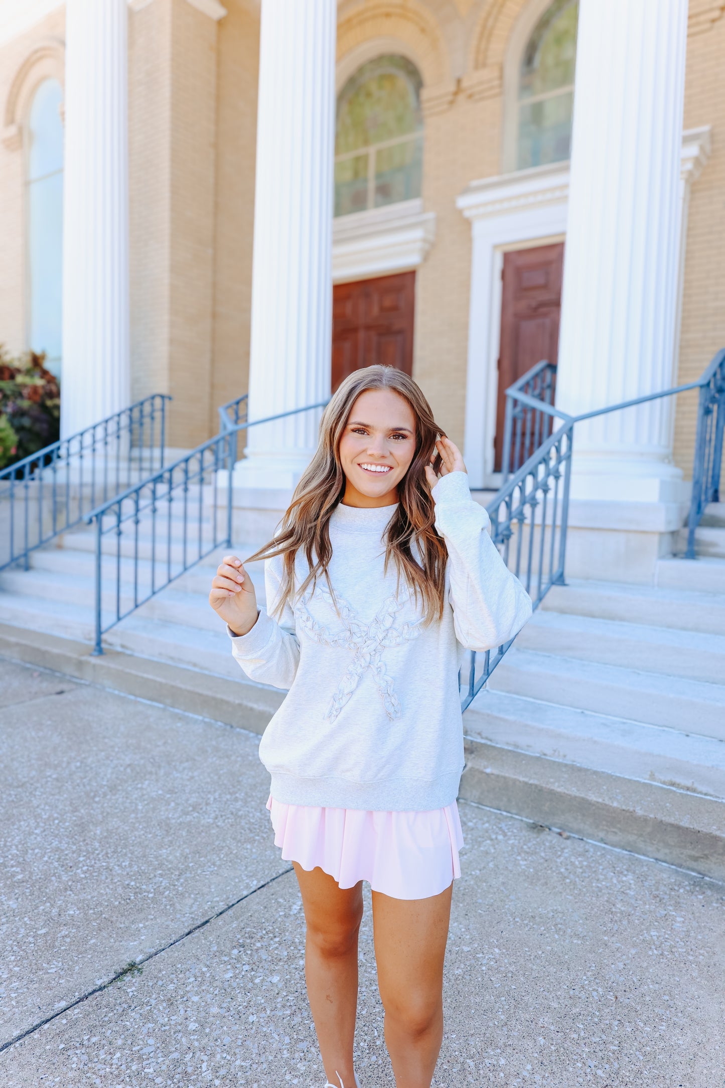Model wearing ruffle bow heather grey sweatshirt.